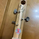 Front view of a three-string guitar with a wooden headstock and the logo of Bob's 3 Stringer on the Cohiba cigar box guitar.