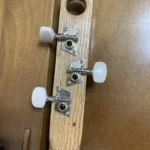 Closed up view of 3 closed gear tuners pegs where they attach to the handcrafted Romeo Y Julieta cigar box guitar