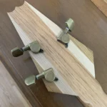 Close-up view of the three closed-gear tuner pegs of Fat Bottom Betty #43, a cigar box guitar handcrafted by Bob.