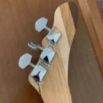 Closed up view of 3 closed gear tuners where they attach to the handcrafted La Palina cigar box guitar by Bob.
