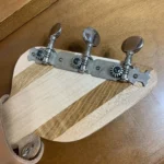 Closed up view of 3 closed gear tuners pegs where they attach to the handcrafted H_UPMANN cigar box guitar