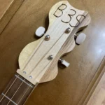 Front view of 3 string guitar with wooden headstock of Punch cigar box guitar by Bob.