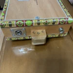 Close up of the bottom with attached Out put jack and strap buttons of the Punch cigar box guitar