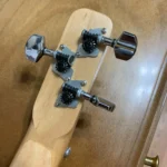 Closed up view of 3 closed gear tuners pegs where they attach to the handcrafted Bances cigar box guitar