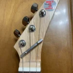 Front view of 3 string guitar with wooden headstock.